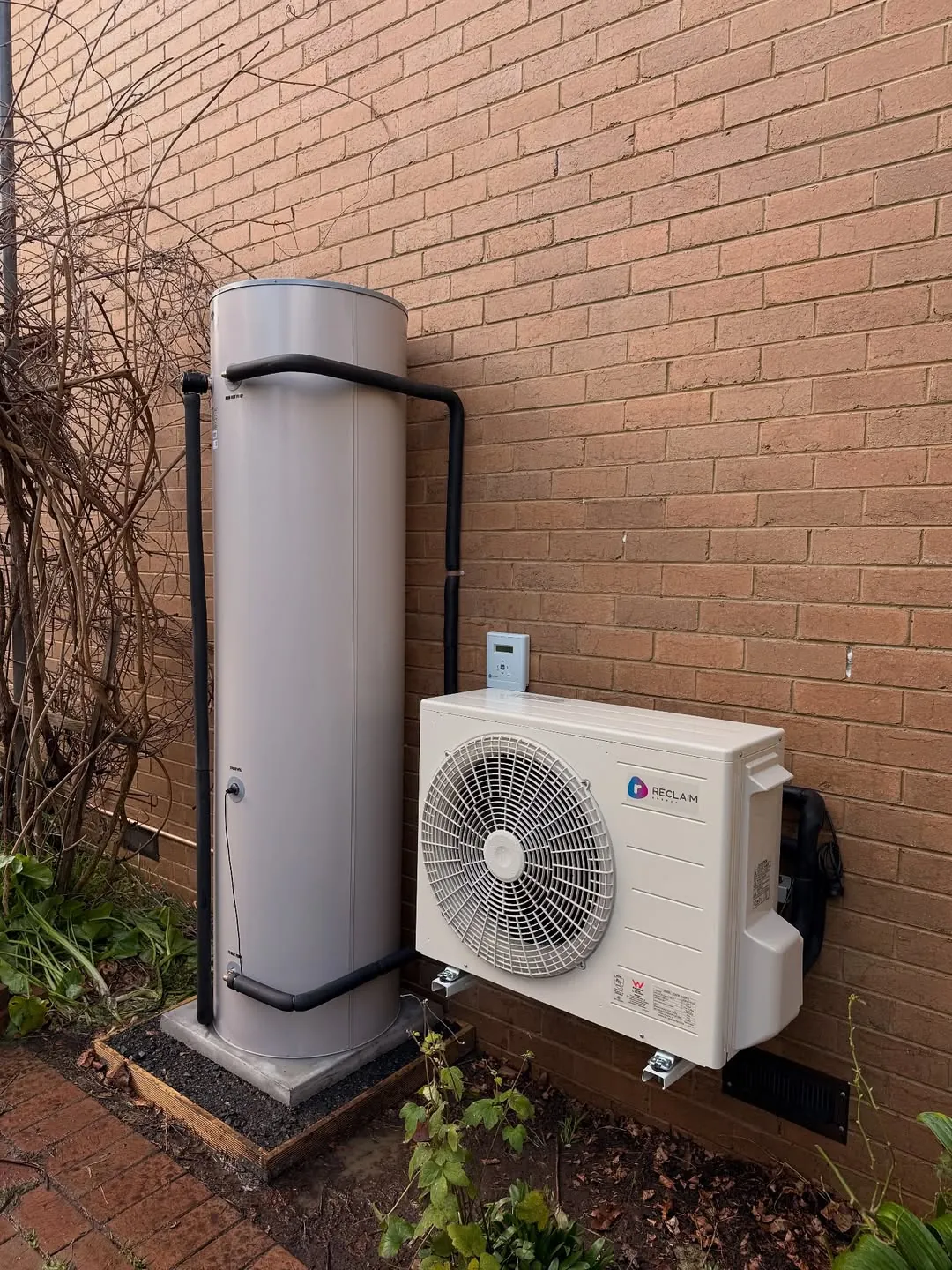 Reclaim CO₂ split heat pump and tank installed against a house wall